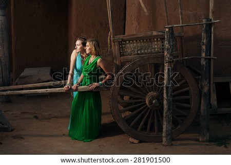 Two women standing near oriental bullock-cart (arba) in scenery of Saray Batu (capital of golden Horde) near modern Astrakhan, Russia