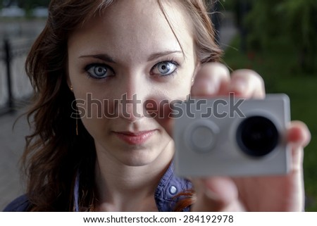 Young women with action camera in hand closeup. Peoples journalism concept.