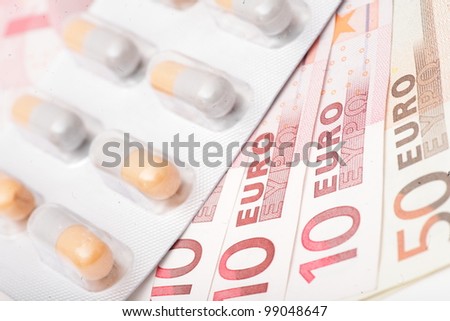 Medical red pills and money close up