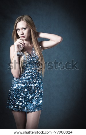 Sexy blonde in party dress over dark background