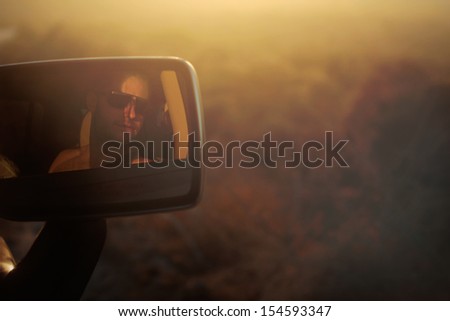 Young man wearing sun glasses during a Roadtrip in the desert on a hot summer day.