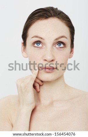 Young woman looking up and thinking in studio