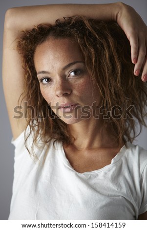 Young woman with hand behind head in studio