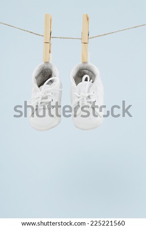 Baby shoes hanging on washing line against blue