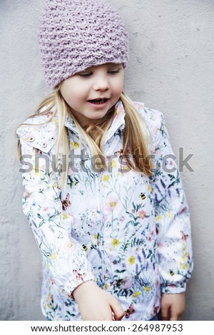 Girl in woolly hat and flowery jacket looking down