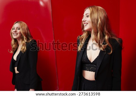 Beautiful woman looking in mirror in red room, smiling