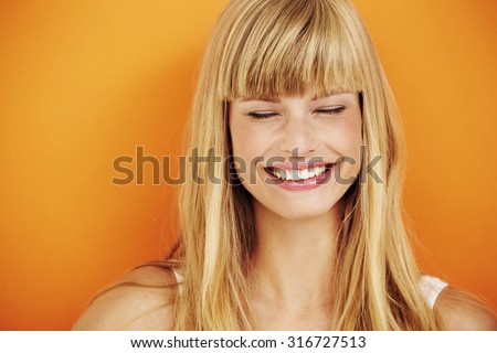 Young blond woman laughing in studio