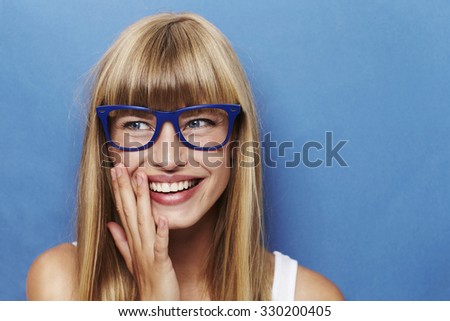 Joy young woman in glasses against blue background