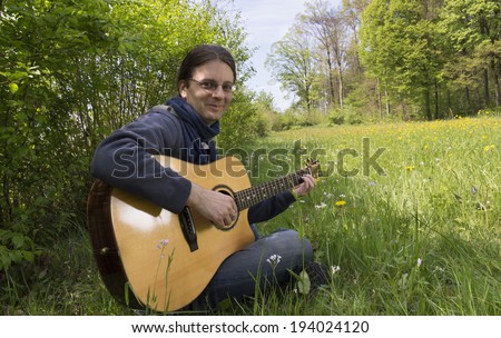 Guitar player outside playing an acoustic guitar