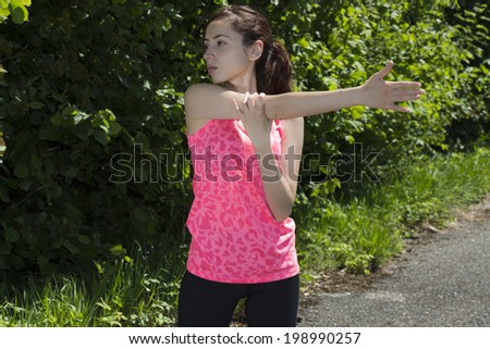 Runner woman stretching her arm after sports outdoors in nature.