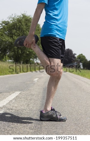 Jogger man stretching his legs after jogging outdoors on the road