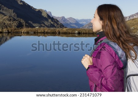 Hiker woman watching the mountain landscape by the side of a lake
