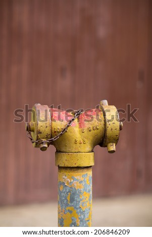 Fire hydrant against  wooden wall on a side street.