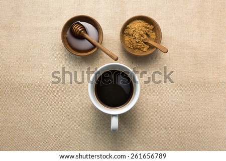 Coffee in white cup with honey and brown sugar in Teak cups