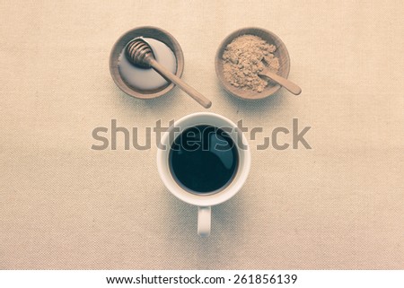 Coffee in white cup with honey and brown sugar in teak cups with vintage look