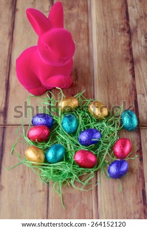 Colorful chocolate Easter eggs on green grass with pink bunny
