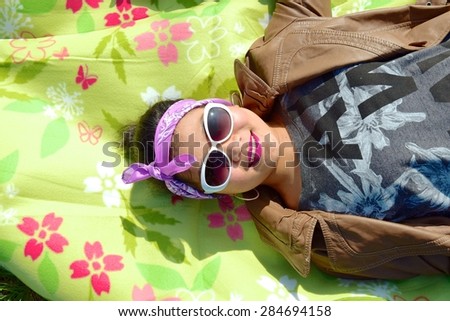 Asian woman laying down wearing sunglasses and bandana