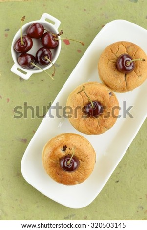 Cherry bread with fresh cherry on green background. Top view.