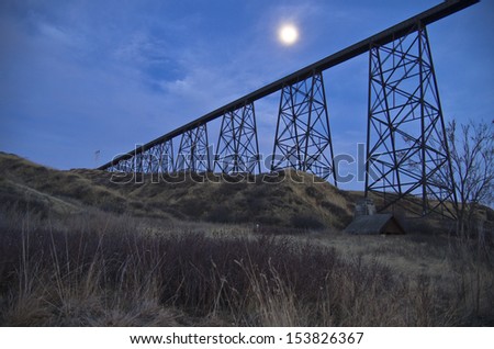 High Level Bridge in Lethbridge, Alberta, Canada with Full Moon and River Valley in Foreground. The High Level Bridge carries trains across the Oldman River.