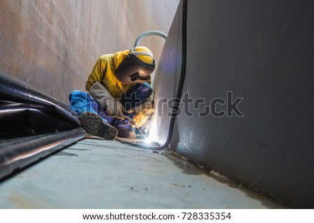 Male  worker wearing protective clothing and repair welding plate industrial construction oil and gas or  storage tank inside confined spaces.