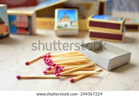 Scattered pink-head matches and a set of souvenir match-boxes.
