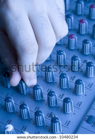 Close up macro of a hand turning mixer knobs. The white balance is changed from raw to give that blueish light effect.