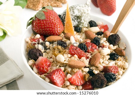 Granola bowl: oats, rice, honey, peanuts, almonds, wax berry, white and red raisins, strawberries, glazed orange peel and fig  . Focus on the center of the bowl.