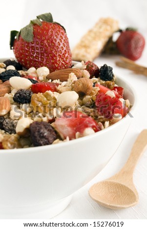 Granola bowl: oats, rice, honey, peanuts, almonds, wax berry, white and red raisins, glazed orange peel and strawberries. Focus on the center of the bowl.