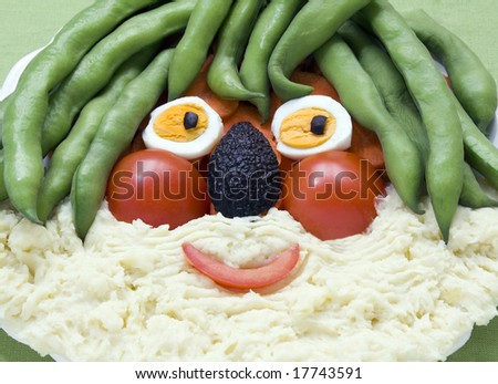 A face made of food for kids fun. Broad beans, tomato, eggs, avocado, carrots and mashed potatoes. All in focus