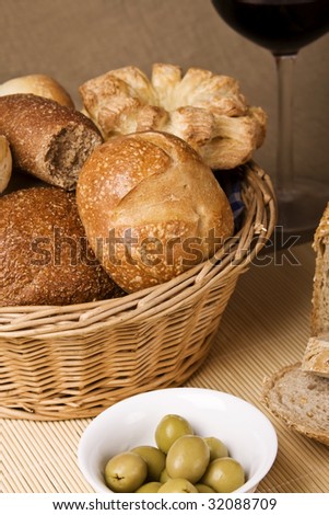 Basket full of bread, olives and a glass of wine. Focus on bread.