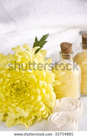 Tranquil scene, composed by bath salts, soap bars, white towels and a yellow chrysanthemum.