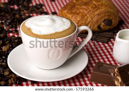 A cup of coffee with chocolate, coffee beans and milk jug. Copy space. Selective focus in the center of the drink.
