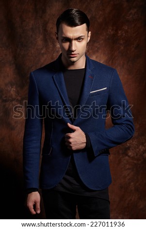 Fashion young man blue suit on brown background.