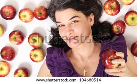 Woman with black hair surround by red apples on white background