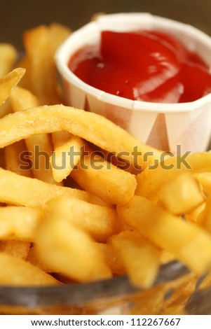 French fries with salt and ketchup in a clear bowl