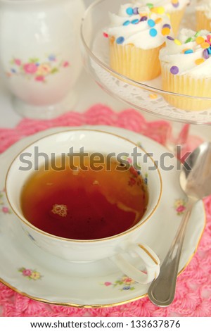 Delicious tea in a nice cup with little cakes