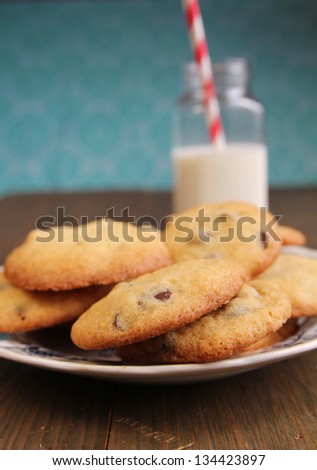 Plate full of chocolate cookies with a fresh bottle of milk with red lined straw