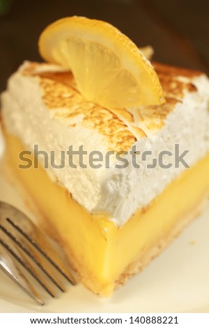 Delicious lemon pie with meringue in a white plate with fork