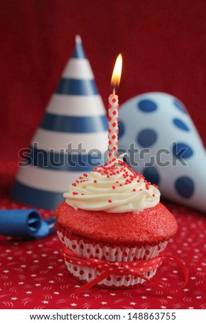 Red velvet cupcake with blue birthday hats on a red background