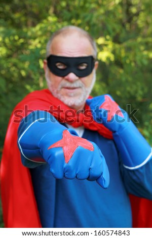 Serious senior super hero with black mask having crossed arms