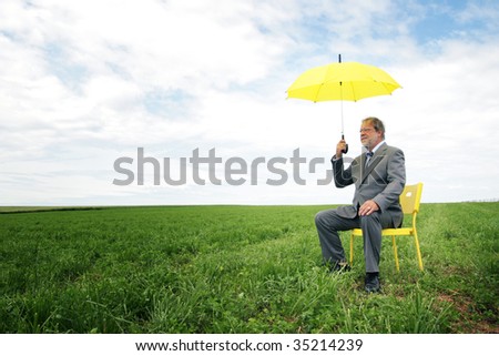 Senior man sit on a yellow chair in a meadow