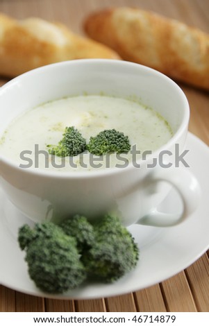 Broccoli soup with fresh broccoli and fresh bread in background
