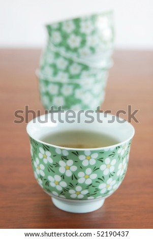 Chinese cup with tea and cups in background