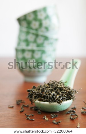 Green tea in a chinese spoon with chinese cups in background