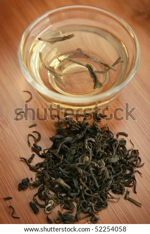 Green tea herbs with clear cup on wooden board