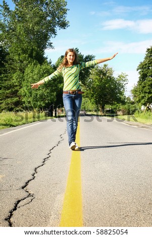 Teenager walking on a yellow line in  the middle of the road
