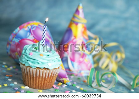 Blue birthday cake with candle on top and hat and twinkle in the background