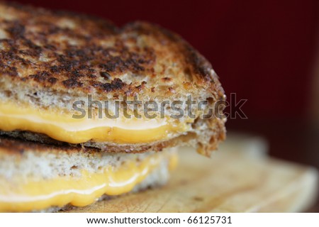 Close up of a grilled cheese with melted cheese in a wood plate
