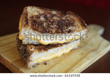 Delicious sandwich with melted orange cheese on a cutting board