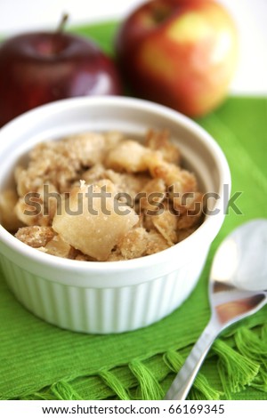 Home made apple crumble in white containers with red  apples in background